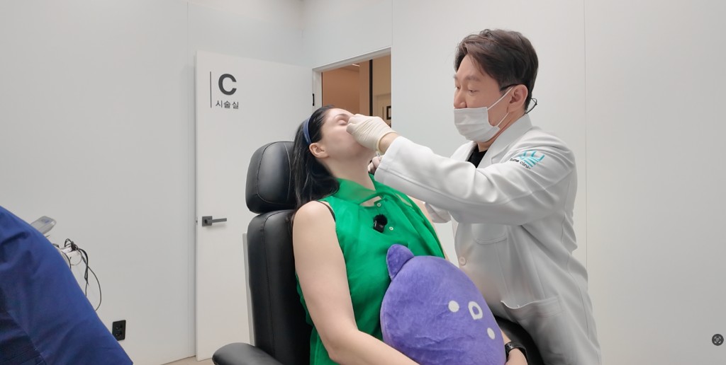 A physician examining a patient's facial structure in the treatment room