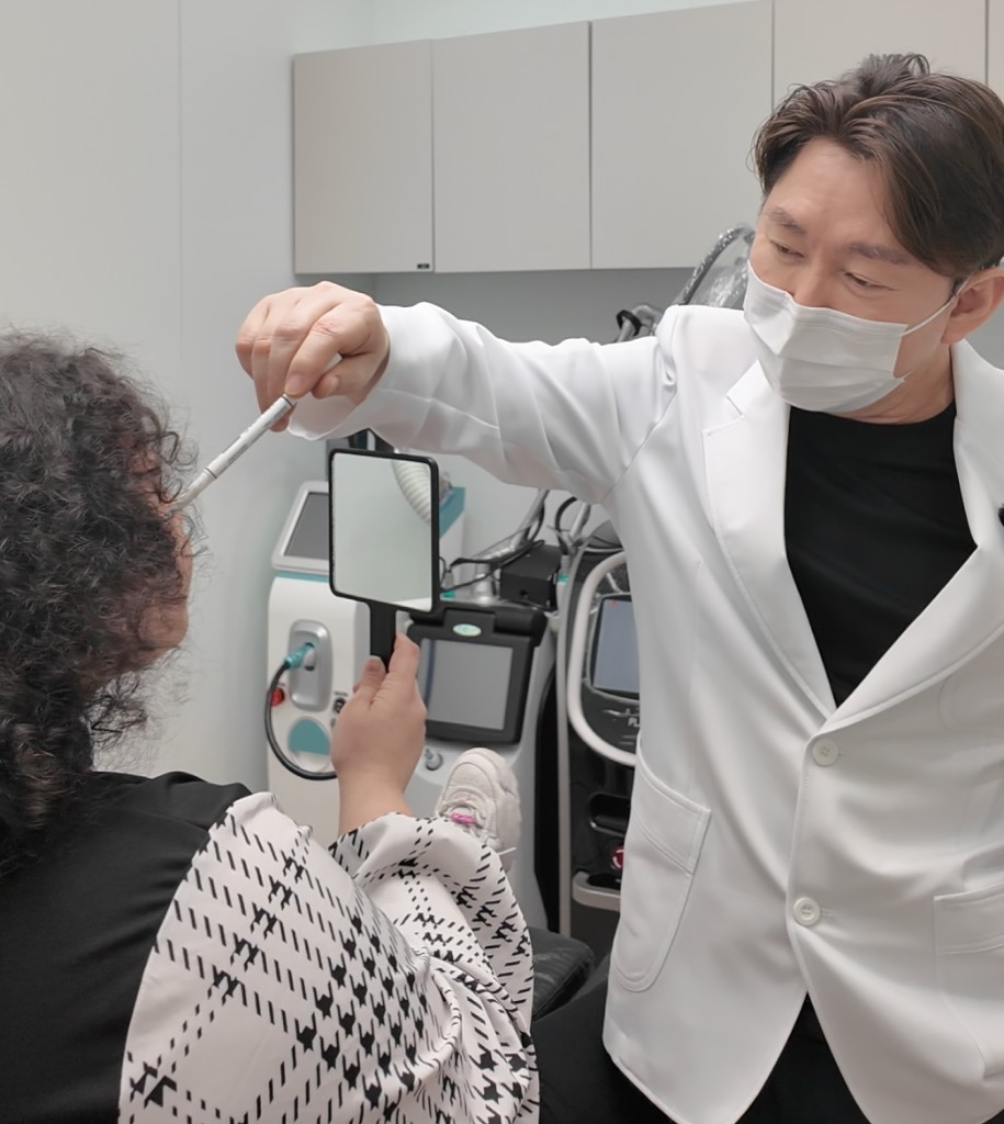 A physician reviewing a patient's facial structure with a hand mirror
