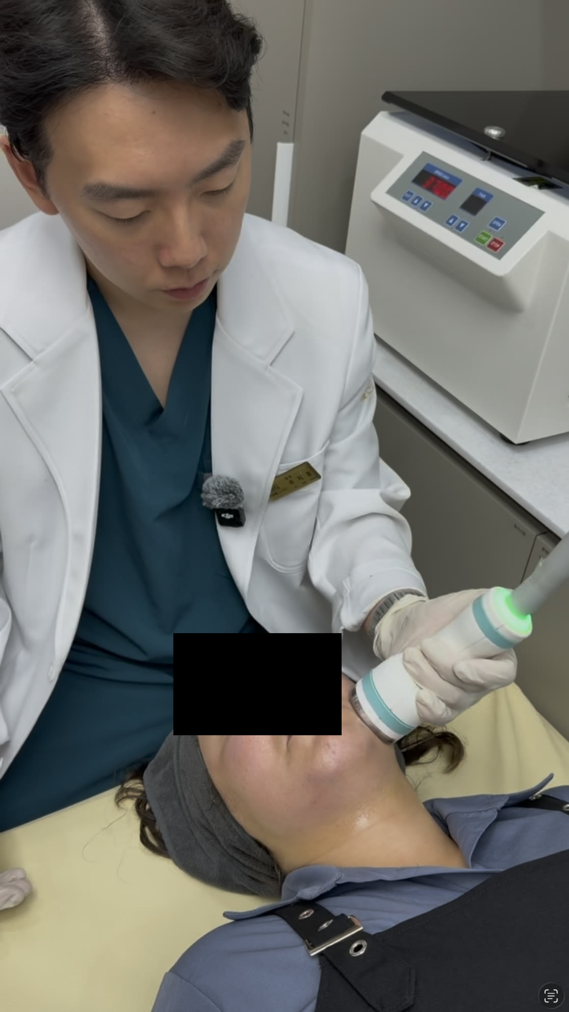 A physician holding the Onda handpiece against the lower face during a session at Tune Clinic; the patient's eyes are masked