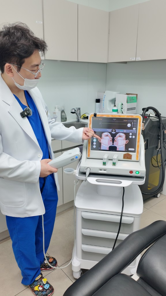 Tune Clinic physician holding the Ultherapy transducer beside the device, facial mapping shown on screen